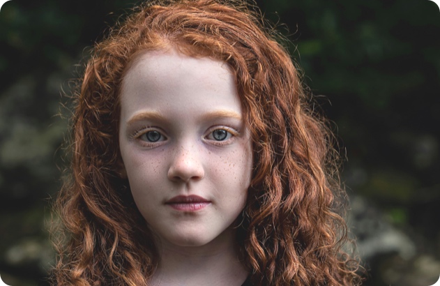 Photo copyright Jennifer Burk, pic shows a young girl with long curly red hair, looking at the camera with a neutral expression